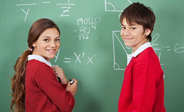 two students at chalkboard being assessed on maths